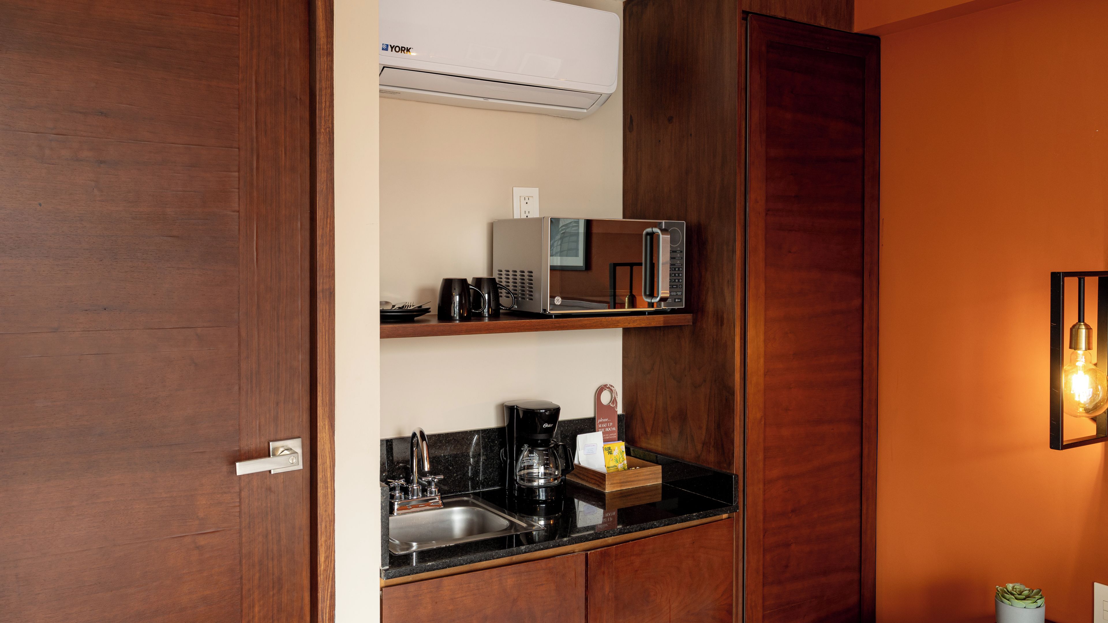A compact kitchenette with a microwave, coffee maker, and a small sink.