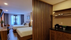 Une chambre d’hôtel moderne avec un plancher en bois, un lit, un bureau et une kitchenette.