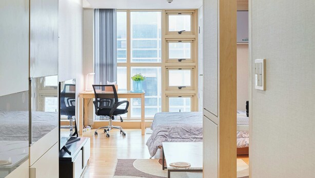 A modern hotel room with a bed, desk, chair, and a large window. - Super and affordable condo in Gangnam offering a boutique hotelstyle experience! (Seoul)