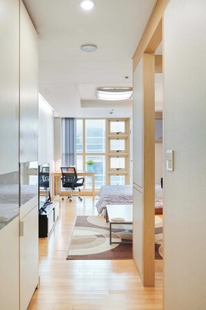 Ein modernes Hotelzimmer mit Bett, Schreibtisch, Stuhl und einem großen Fenster.