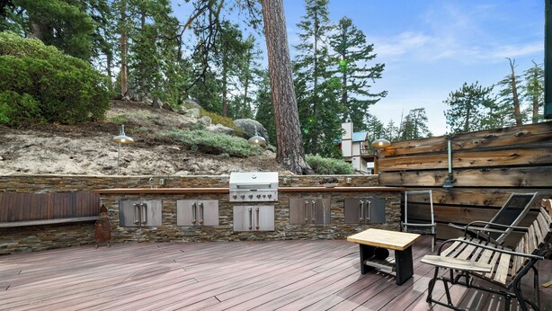 Eine Terrasse im Freien mit Steinmauer, Holzkohlegrill und Sitzbereich.