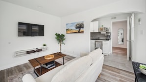 A modern living room with a sofa, a coffee table, and a TV mounted on the wall. - 15 min. to Detroit center - bathroom with floor heating - free curbside parking (River Rouge)