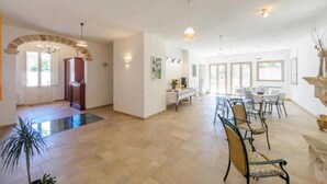 A spacious dining area with a long table and chairs, a chandelier, and a view of the outdoors through large windows. - Aunts' Garden - Sun Room (TRICASE (LE))