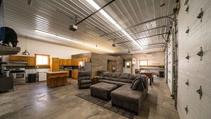 A spacious living area with a large sectional sofa, a kitchen with wooden cabinets, and a high ceiling with exposed beams. - Amazing Lake of the Woods 2-bedroom cabin with loft and man cave in Baudette, MN (Williams)
