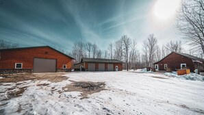 A snow-covered parking lot with three wooden buildings, each with a garage door. - Amazing Lake of the Woods 2-bedroom cabin with loft and man cave in Baudette, MN (Williams)