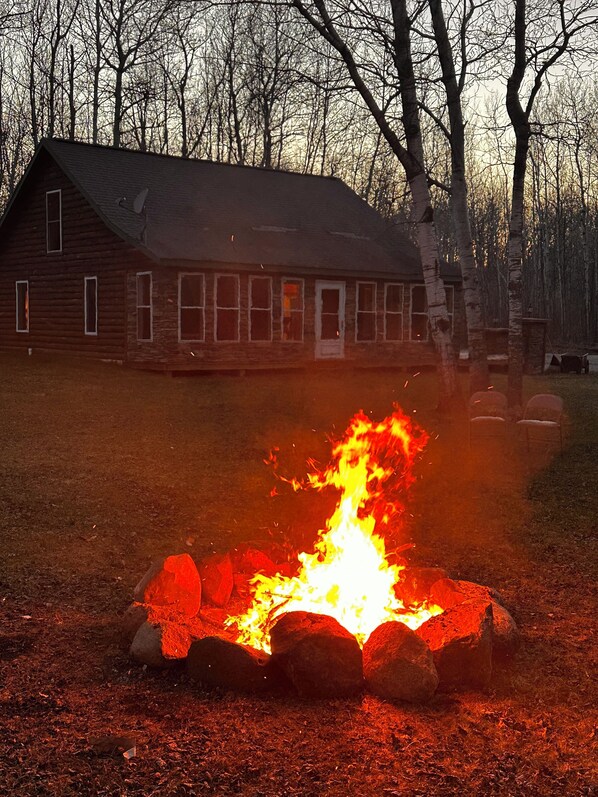 A rustic cabin with a fire pit in front. - Amazing Lake of the Woods 2-bedroom cabin with loft and man cave in Baudette, MN (Williams)