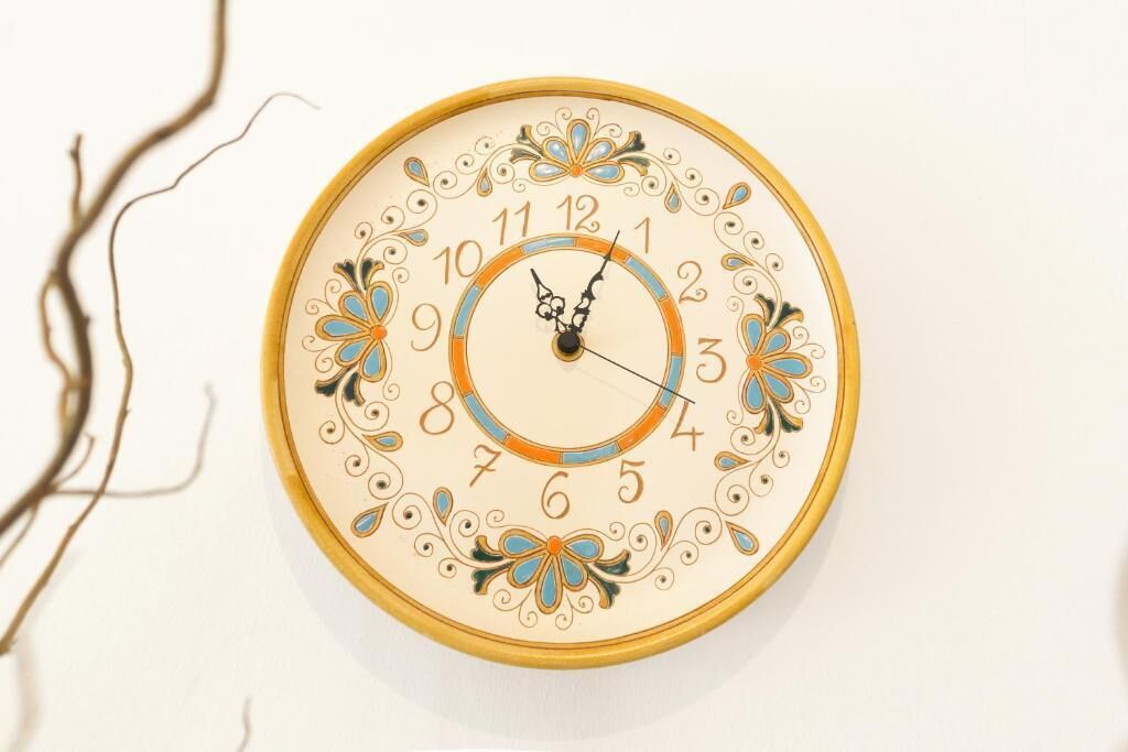 A wall-mounted clock with ornate floral designs and numbers.