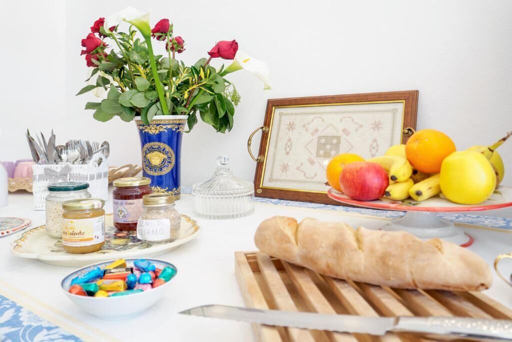 Uma mesa com diversos alimentos, um vaso com flores e um quadro emoldurado.
