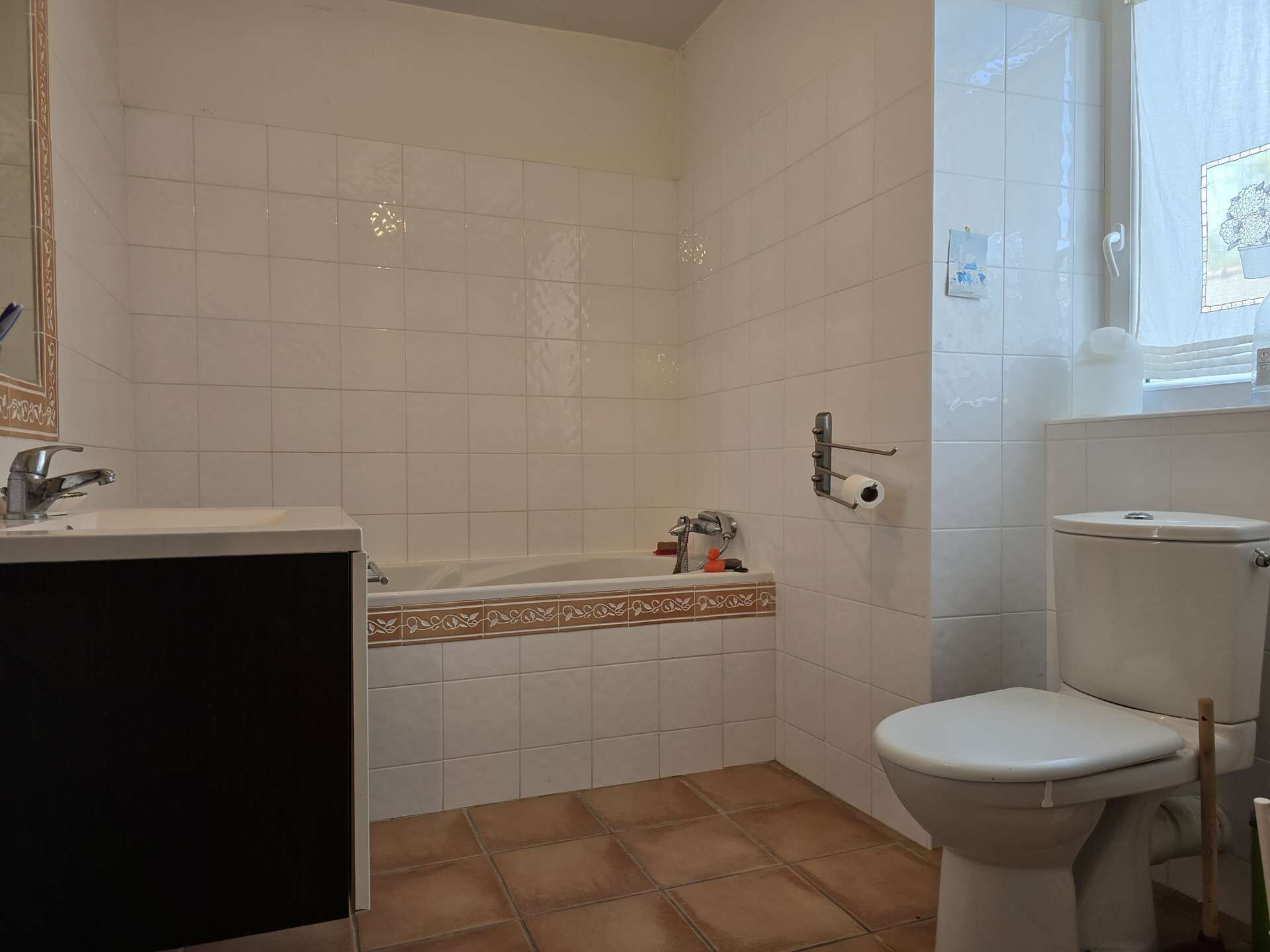 A bathroom with white tiles, a bathtub, a toilet, and a sink.