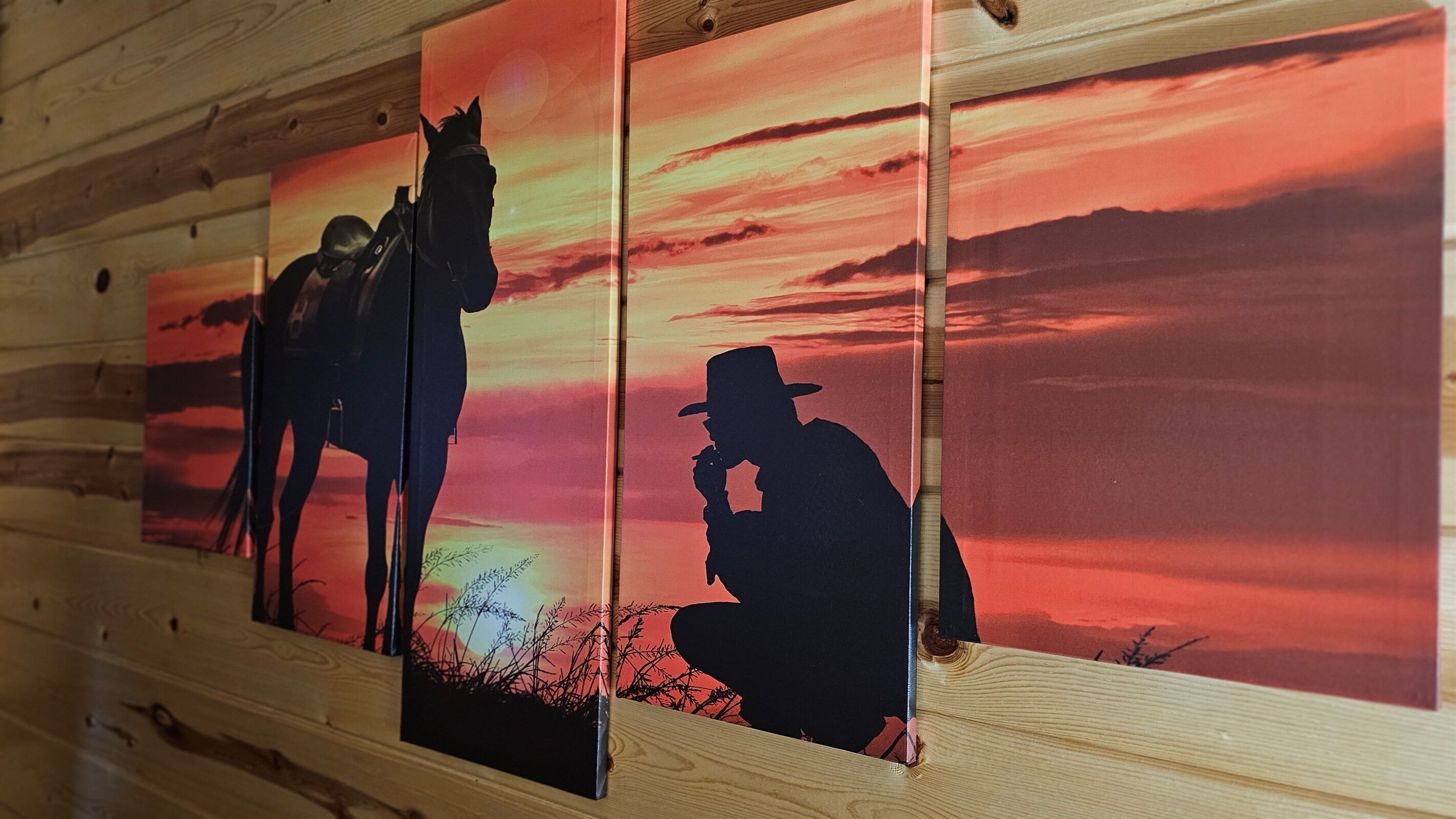 A wooden wall with three framed artworks depicting silhouetted figures of a man with a horse and a man in a hat.