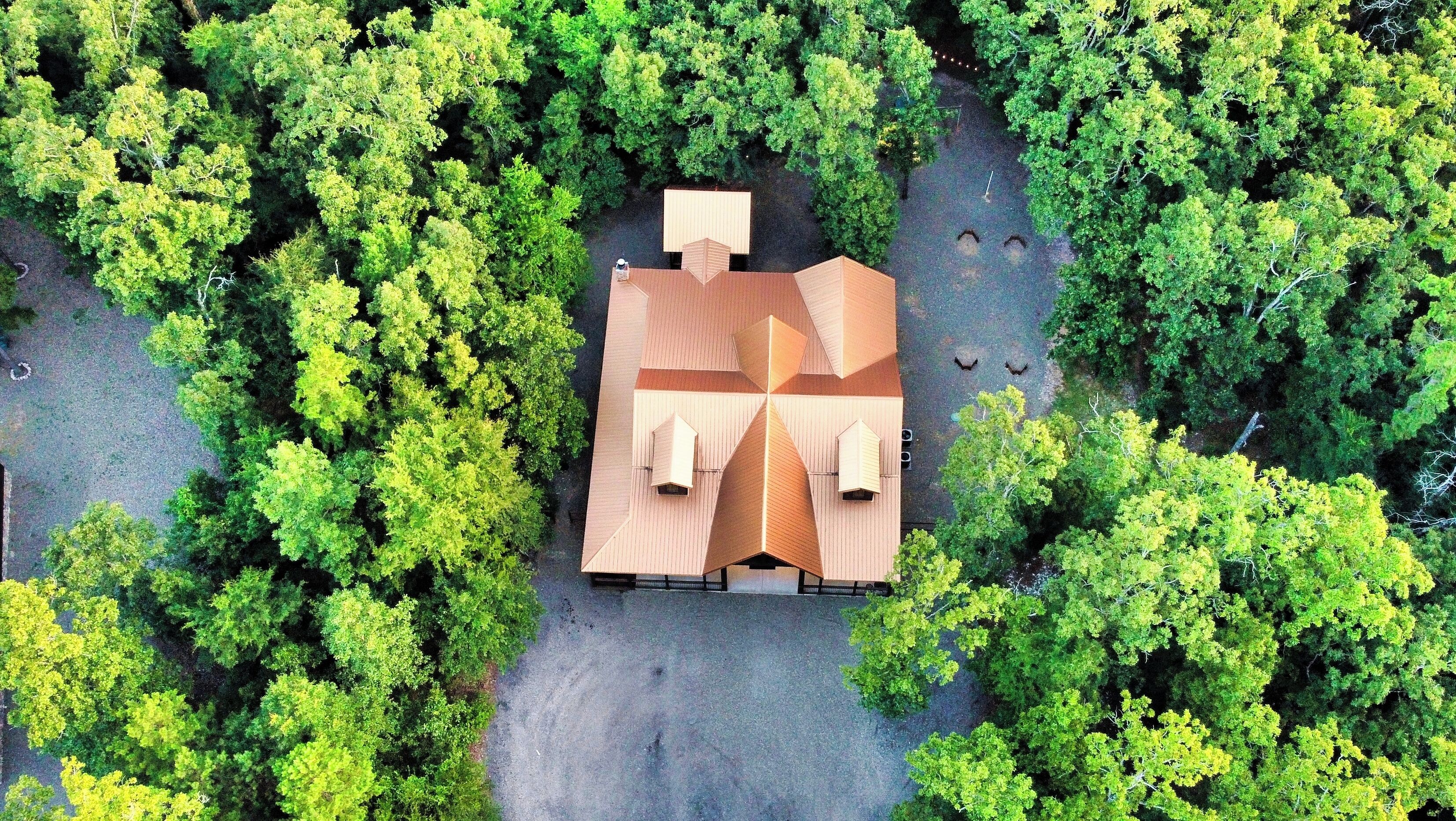 An aerial view of a house surrounded by dense green trees.