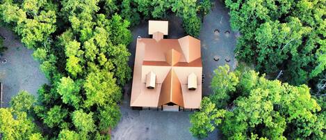 An aerial view of a house surrounded by dense green trees.