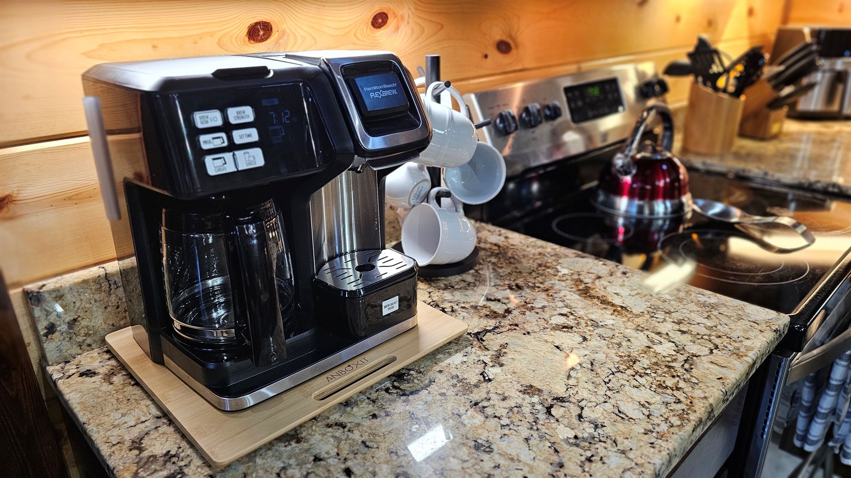 A coffee maker with a digital display on a granite countertop in a kitchen.