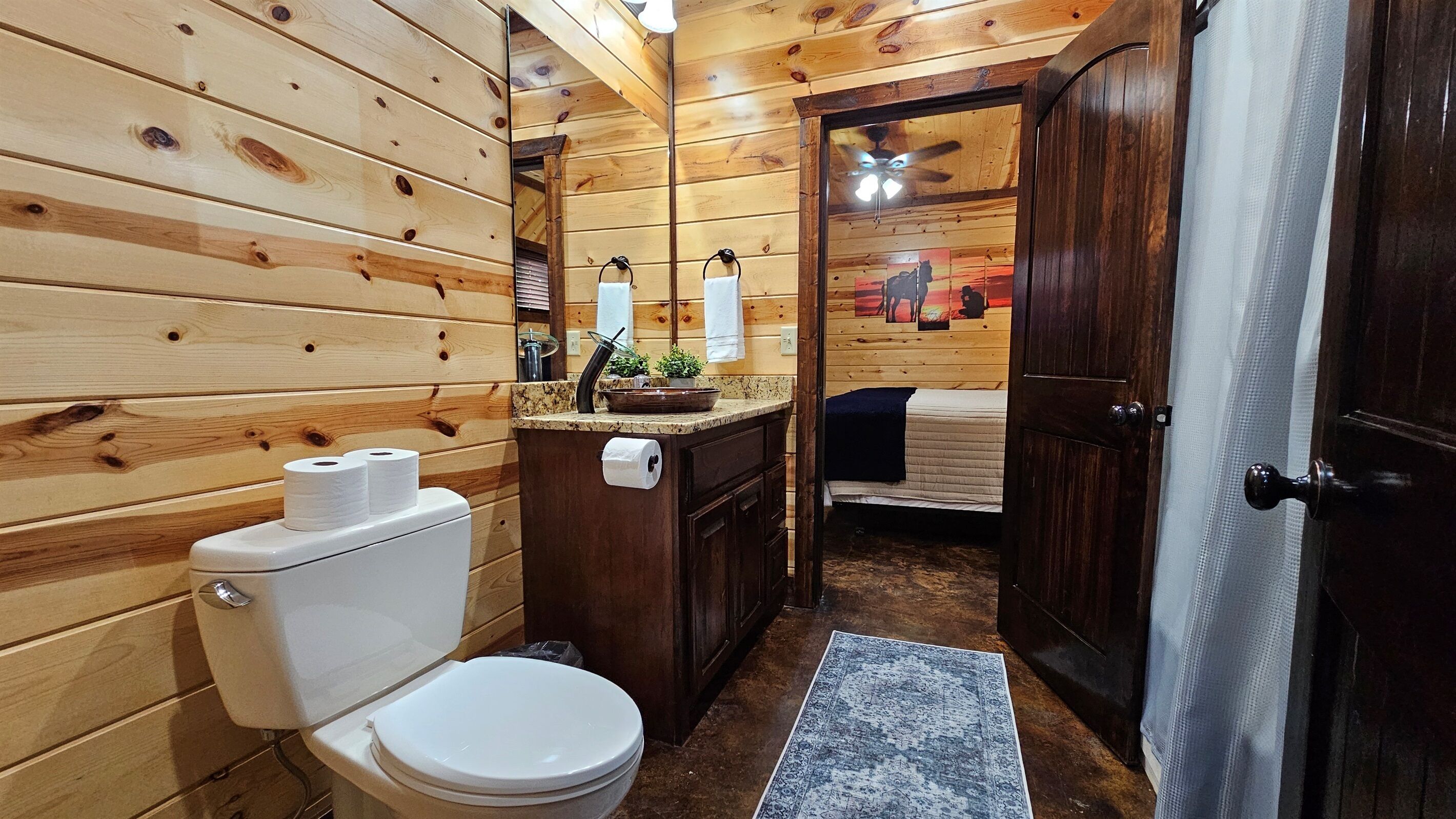 Une salle de bain rustique, aménagée dans une cabane en bois, avec des toilettes, un lavabo et une petite fenêtre.