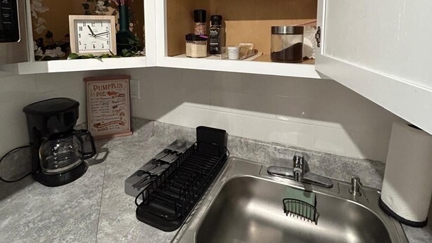 A kitchen with a stainless steel sink, a coffee maker, and a built-in oven. - Serene studio (Tampa)
