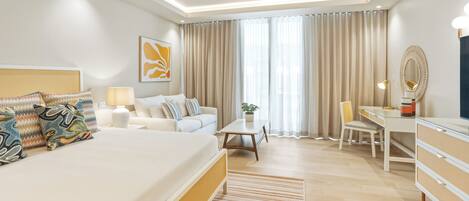 Habitación de hotel moderna con una cama grande, un escritorio, una silla, una lámpara y una planta en maceta.