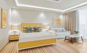 A modern hotel room with a bed, bedside tables, a sofa, a coffee table, and a potted plant. - Sapphire Sands by Bay Gardens Resorts (Gros Islet)
