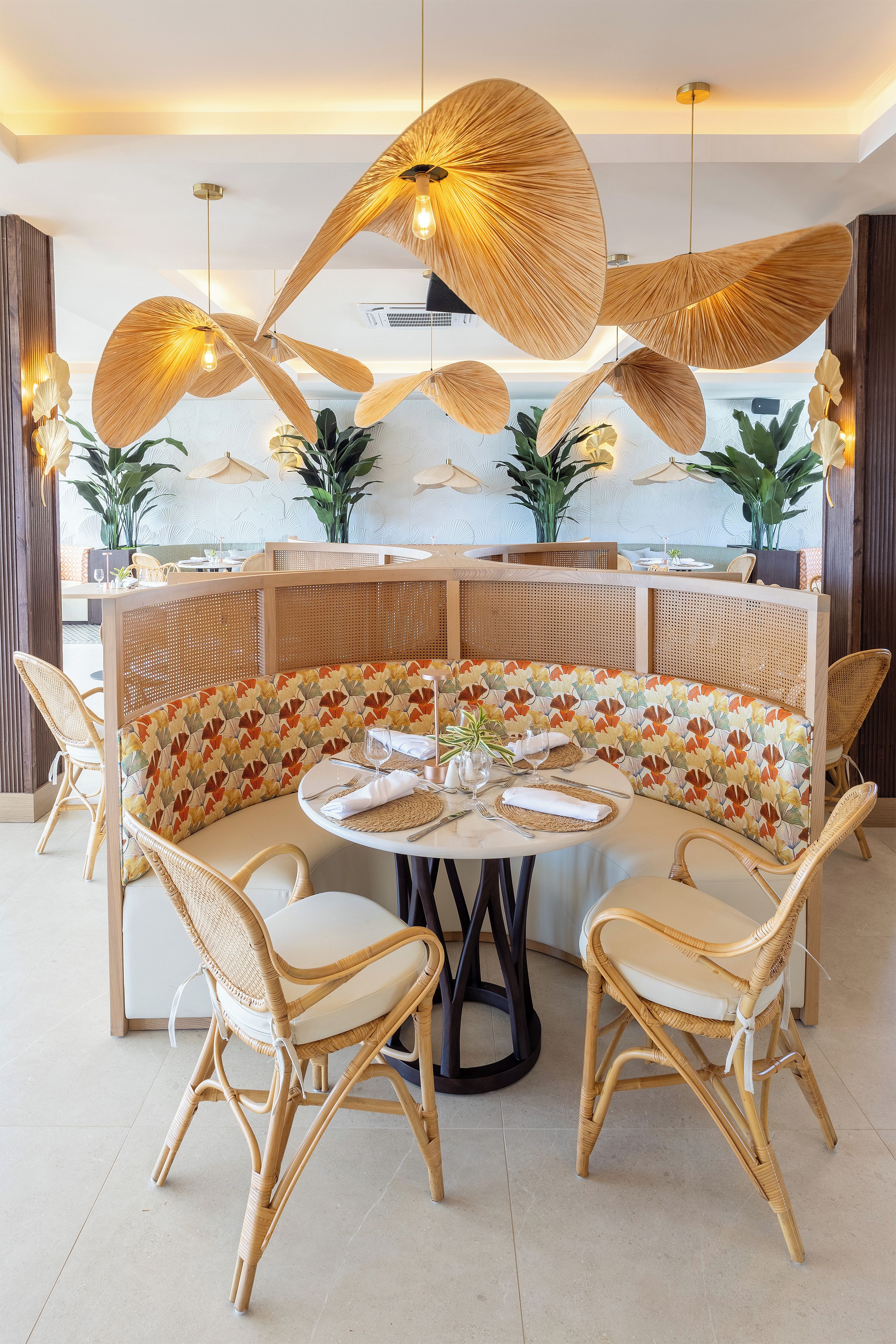 A round dining table with a woven bench, surrounded by wicker chairs.