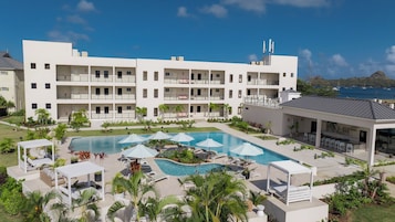Un hotel de varios pisos con piscina, tumbonas y sombrillas.