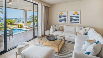 Ein modernes Wohnzimmer mit einem Glastisch, einer Couch und Blick auf ein Schwimmbad und den Ozean.