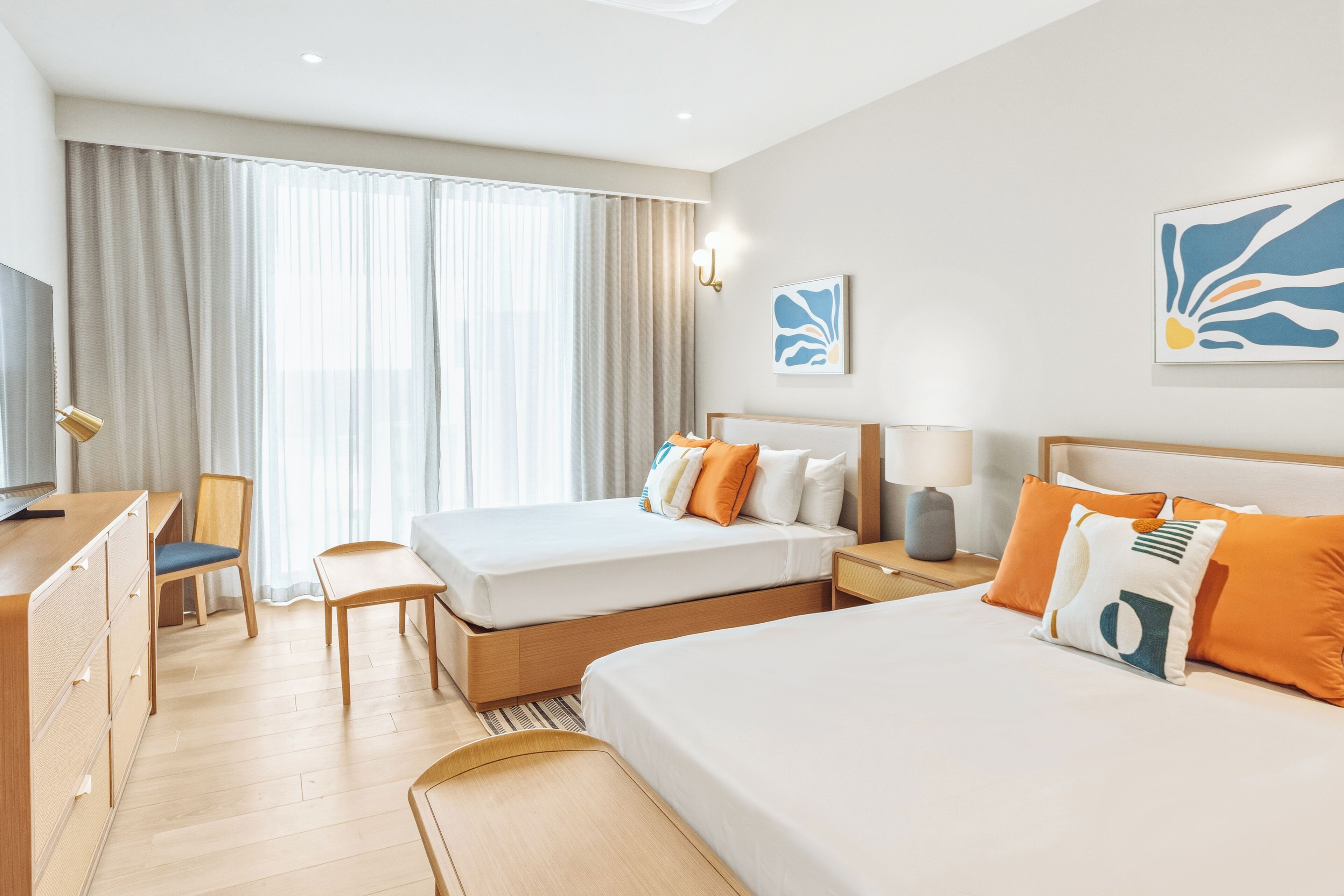 Une chambre d’hôtel avec deux lits, un bureau, une chaise et un téléviseur.