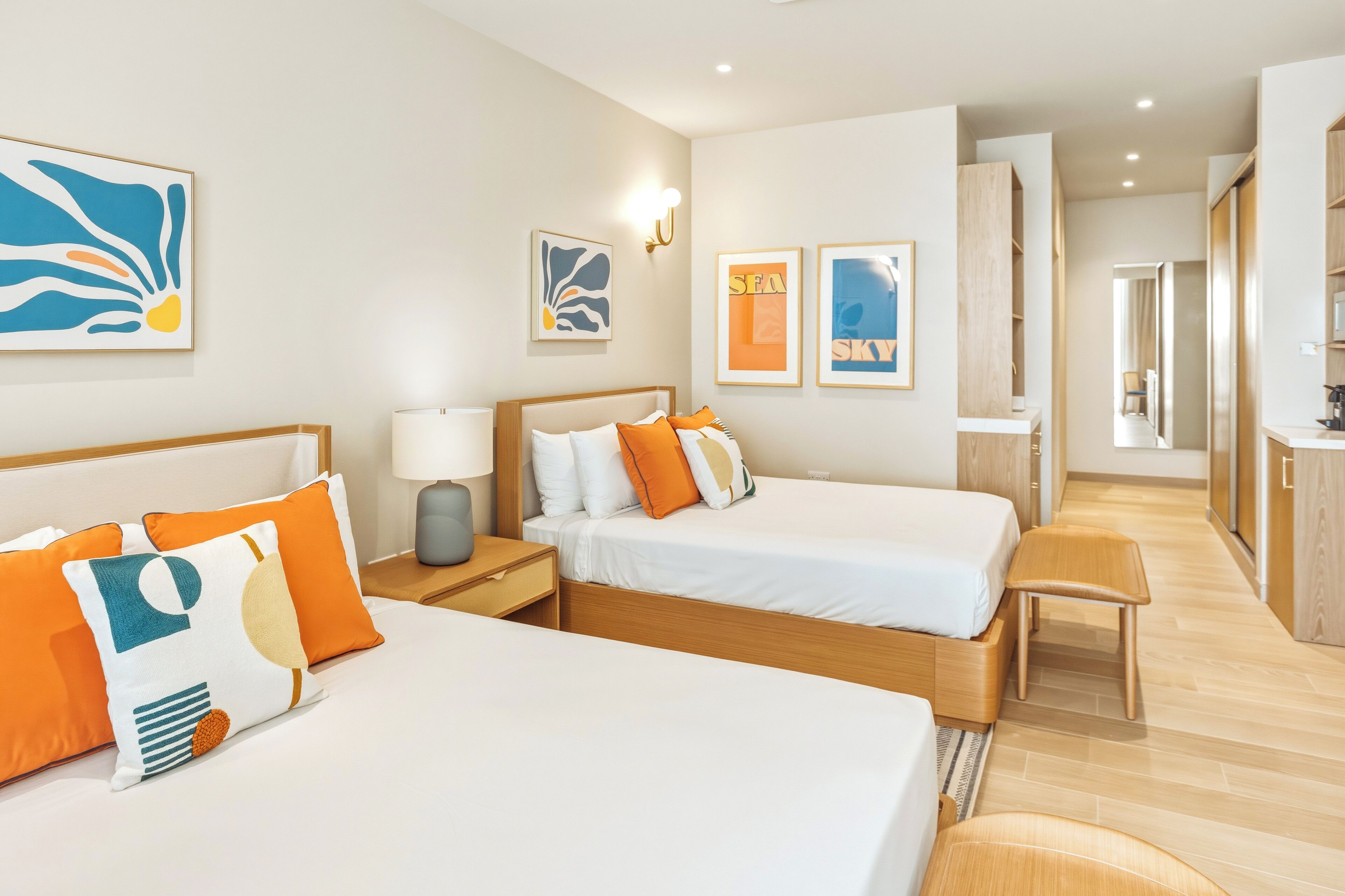 Quarto de hotel com duas camas, uma escrivaninha e vista para o corredor.