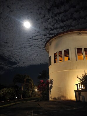 A building with a round shape, multiple windows, and a visible moon in the sky.