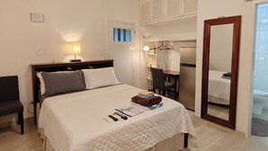 A bedroom with a bed, bedside table, lamp, ceiling fan, and a mirror. - Studio- Spacious garden area / on-site car rental (Saint John's)