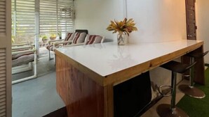 A modern kitchen with a wooden island, bar stools, and a view of the adjacent dining area. - Studio- Spacious garden area / on-site car rental (Saint John's)