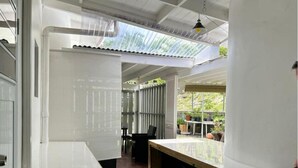 A modern kitchen with a central island, a dining area with a table and chairs, and a view of a garden through large windows. - Studio- Spacious garden area / on-site car rental (Saint John's)