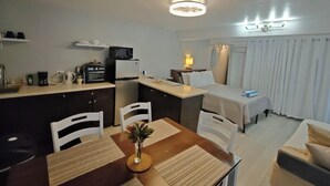 Una habitación de hotel compacta con kitchenette, zona de comedor, cama y baño.