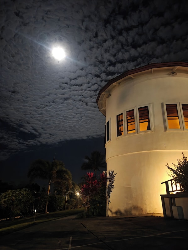 A building with a round shape, multiple windows, and a visible moon in the sky.