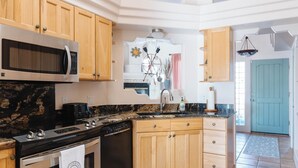 A kitchen with wooden cabinets, a microwave, a stove, and a dishwasher. - Charming 3-bedroom house with AC, WiFi in tranquil Cottonwood (Cottonwood)