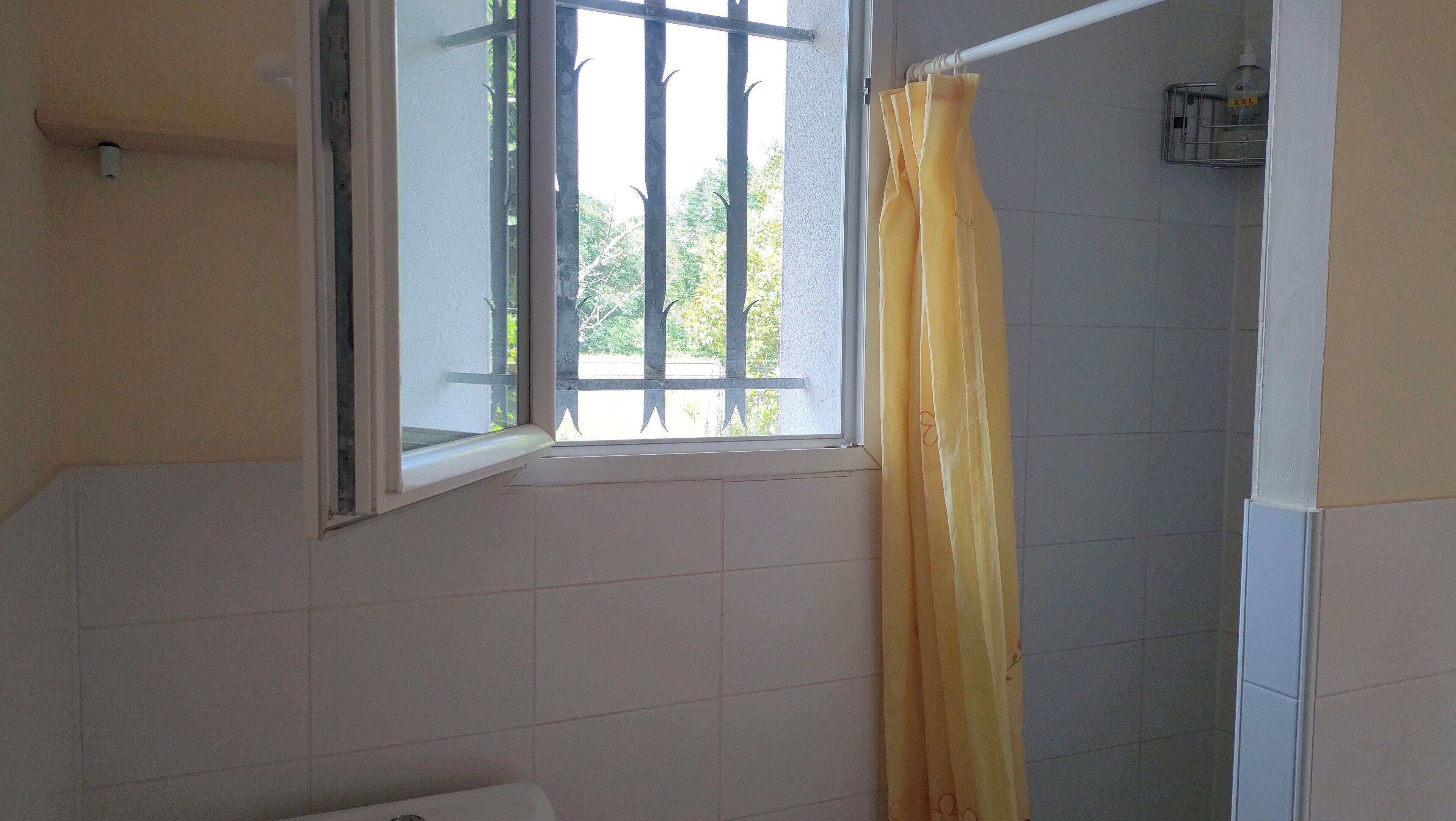 Un baño con ventana, cortina de ducha y retrete.