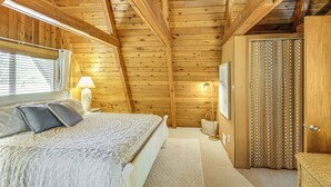 A wooden-paneled bedroom with a bed, bedside lamp, and a window with blinds. - Canal Across Street: Family Cabin in Breezy Point! (Pequot Lakes)