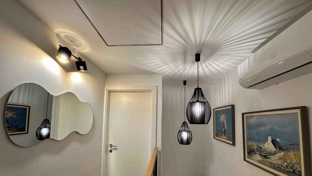 A hallway with a wooden floor, a white door, a wall-mounted mirror, and three hanging pendant lights. - Holiday home with air conditioning (Jadranovo)