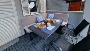 A balcony with a table set for breakfast, including fruits, pastries, and drinks. - Holiday home with air conditioning (Jadranovo)