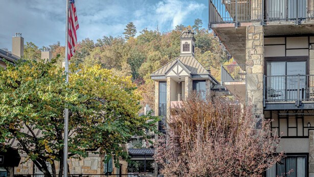 A building with a stone facade, a balcony with railings, and a flagpole with an American flag.