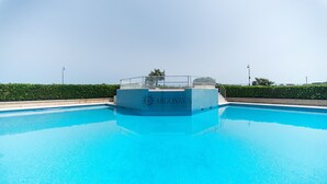 A clear blue swimming pool with a glass-enclosed area labeled "ARGONAVIS" and a staircase leading into the pool.