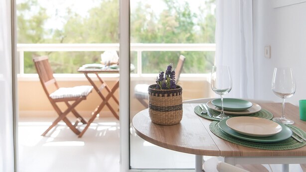 A dining table with plates, glasses, and a woven basket with flowers.
