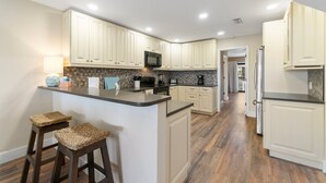 Cocina moderna con gabinetes blancos, una isla central y un microondas.