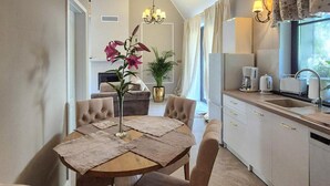 Une cuisine moderne avec un coin repas, comprenant une table ronde entourée de chaises, une plante en pot et un lustre.