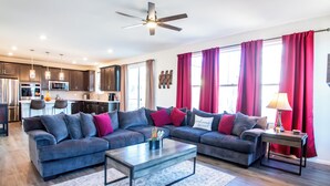 Ein modernes Wohnzimmer mit einem Ecksofa, einem Couchtisch und einer Küche im Hintergrund.