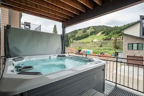 A hot tub on a balcony with a view of a mountainous landscape.