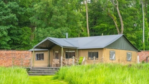 Une cabane rustique avec un toit en pente, une véranda avec des chaises et un mur en briques.