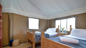 Une chambre avec deux lits en bois, une grande fenêtre et un auvent au plafond.