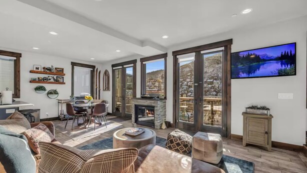 A spacious living room with a fireplace, large windows, and a television. - Dual-Unit Mountain Retreat: 4BR,  Prime Location, Sleeps 10, Historic Charm & Modern Luxury, Steps to Main St! (Park City)