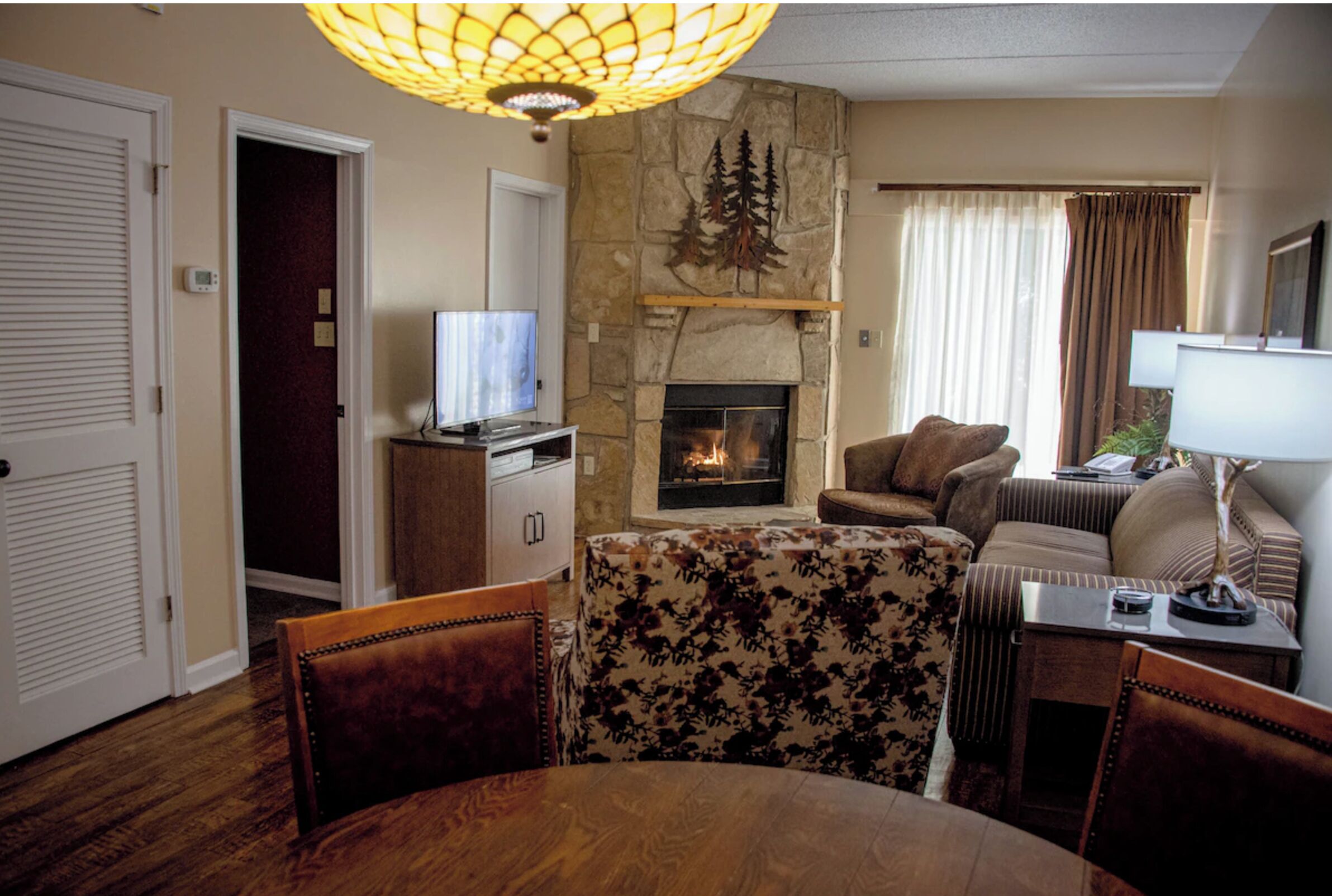 Una sala de estar con chimenea, televisor y comedor con mesa y sillas.