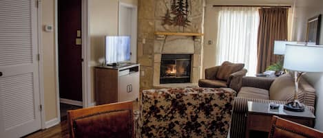 A living room with a fireplace, a television, and a dining area with a table and chairs.