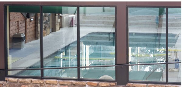 A view through a window with a stone base, reflecting a building with a staircase and a covered area.